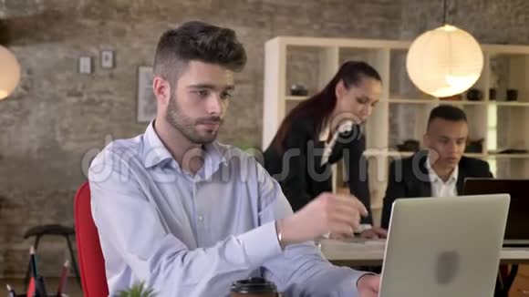 年轻的商人正在办公室里看着笔记本电脑看着摄像机微笑着人们正在与科技建立联系视频的预览图