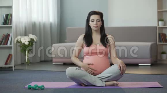孕妇坐在瑜伽垫上做呼吸练习和按摩腹部视频的预览图