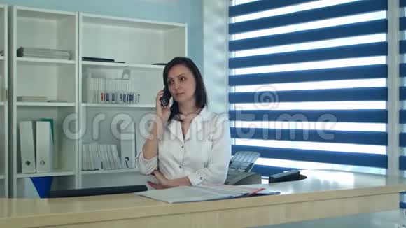 微笑的女护士在接待处接电话视频的预览图