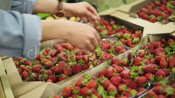年轻女子购物在商店里拿起一小盒新鲜草莓的塑料新鲜水果视频的预览图