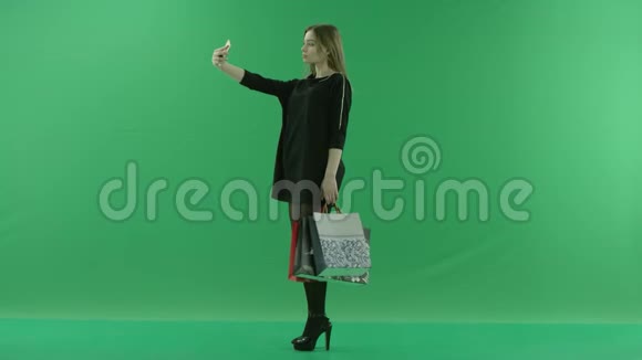 带包的年轻女士在智能手机上自拍彩色钥匙绿色背景视频的预览图