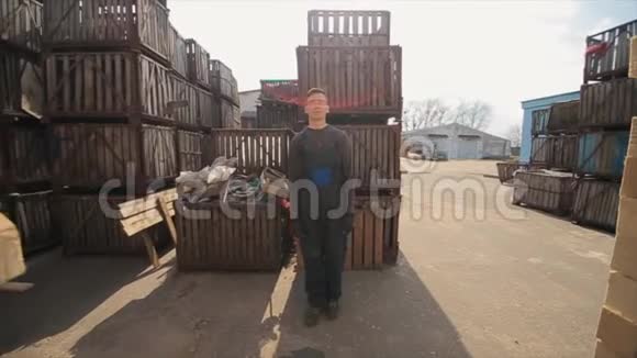 一位穿制服的年轻工人在配电室外仓库的木托盘之间行走慢动作视频的预览图