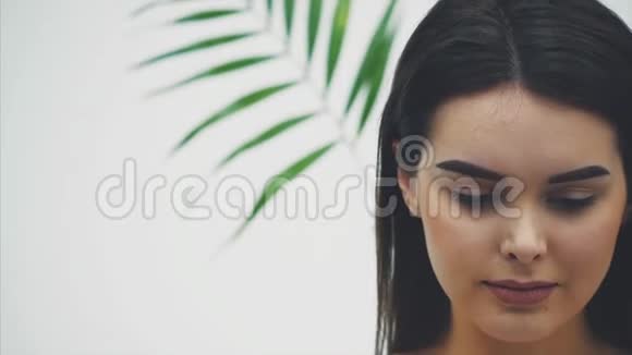 美丽的年轻女人完美的皮肤和自然的化妆摆在植物前面热带绿叶背景视频的预览图