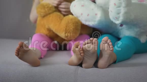 儿童腿观女性朋友坐在沙发上玩泰迪视频的预览图