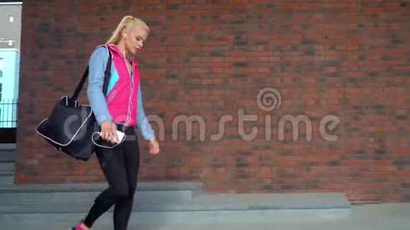 年轻有魅力和运动的金发女孩带着一个运动包在户外散步保健健身和生活方式视频的预览图