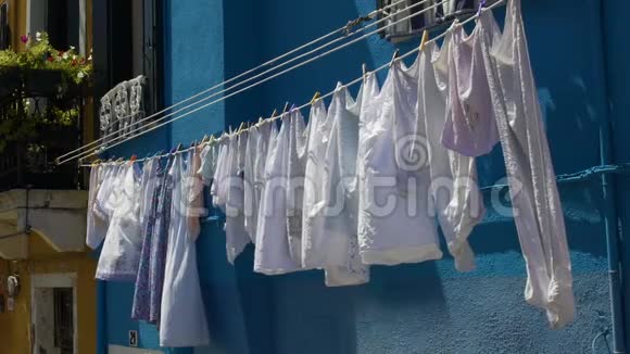 干净的衣服随风飘动挂在明亮的蓝色房屋立面上视频的预览图