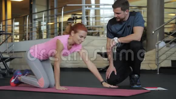 健身女士在体育俱乐部和教练一起做木板运动视频的预览图