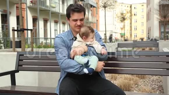 年轻的父亲和孩子坐在长凳上视频的预览图