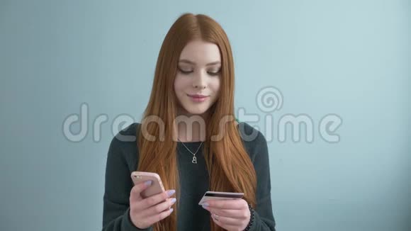 年轻漂亮的红发女孩在网上购物网上银行使用智能手机购物并提供信用视频的预览图