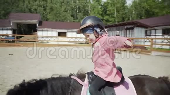 快乐的小女孩正在马术俱乐部骑一匹黑色的小马视频的预览图