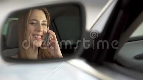 快乐的女人坐在汽车上和父母在智能手机上聊天视频的预览图