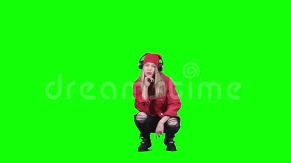 十几岁的女孩坐在她的头发上听着耳机上的音乐绿色屏幕视频的预览图
