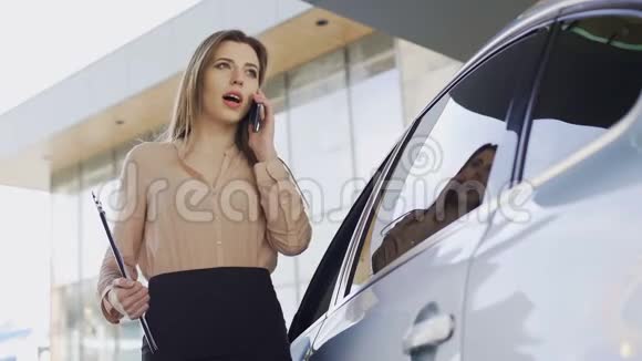 自信的女商人在智能手机上与客户在停车场附近交谈视频的预览图