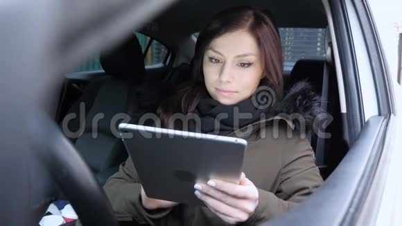 坐在车里的年轻女子在平板电脑上打字视频的预览图