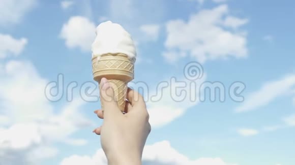 蓝天背景下的女性手拿着冰淇淋筒清爽的甜点视频的预览图