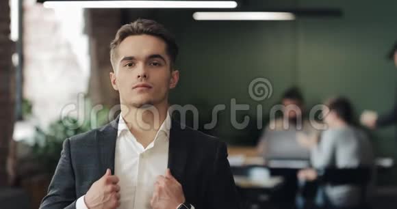 年轻成功商人在繁忙的办公室的肖像英俊的男员工看着相机微笑商务视频的预览图