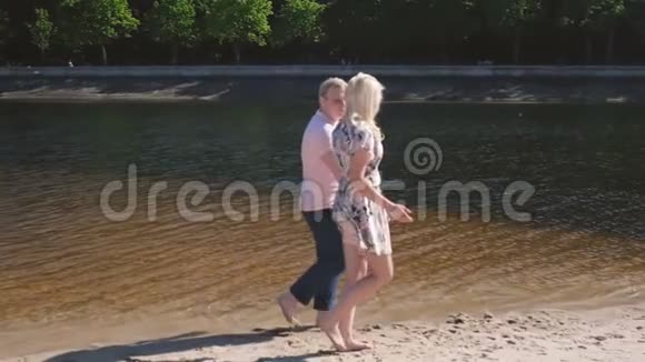 阳光明媚的一天美丽的情侣在河边散步视频的预览图