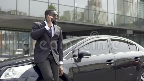 英俊的美国黑人男子在办公室附近微笑着打电话视频的预览图