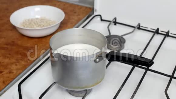 在盘子里煮燕麦片煮牛奶和燕麦片特写用勺子搅拌麦片视频的预览图