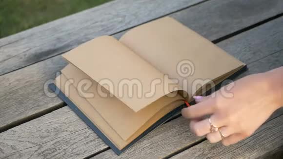 女人手慢慢地转动一本带有书签的干净书的页面一本米色的笔记本手指上的环视频的预览图