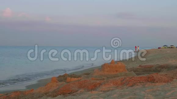 日出时两个女孩沿着海边散步前面是沙质蓖麻视频的预览图