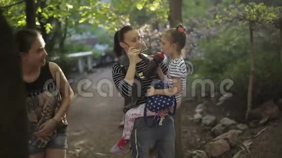 母亲带着两个女儿漫步在公园里停下来解渴视频的预览图