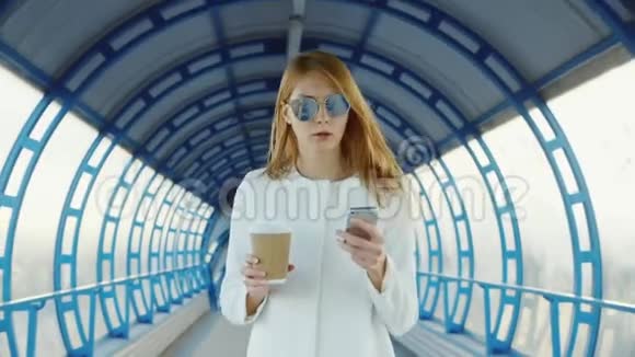 一切都在进行中商务女性拿着一杯咖啡和电话很快就走上了玻璃隧道视频的预览图