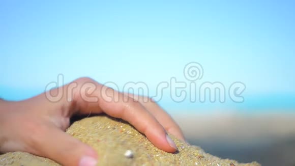手特写放沙沙子在蓝色的海洋上流过暑假海滩度假视频的预览图