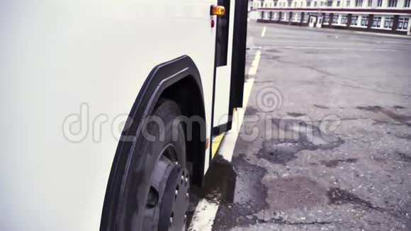 在灰色沥青背景下白色巴士的侧视图与开门和巴士轮场景关闭客车视频的预览图