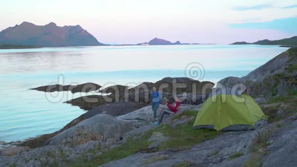 峡湾岸边帐篷附近的游客视频的预览图