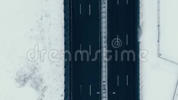 冬季在海湾上空降雪时垂直沿公路桥的空中观景视频的预览图