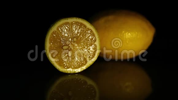 一片柠檬和一整片多汁的柠檬放在一张深色的镜子桌上高清高清视频的预览图