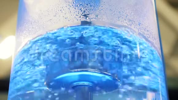 用霓虹灯背光和金属管在大型玻璃冷却器中沸腾水媒体冷却器中最纯净水的特写镜头视频的预览图