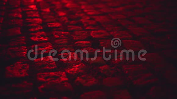 夜晚被红光鹅卵石铺砌的街道照得湿漉漉的视频的预览图