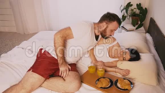 早晨卧室里的男人叫醒了他妻子在床上吃早餐视频的预览图