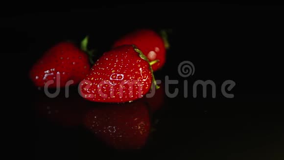 三个草莓躺在黑暗的背景上一滴水滴在草莓上视频的预览图