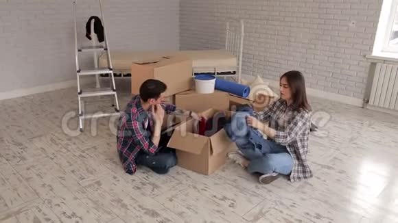 一对快乐的夫妇在他的新公寓里坐在地板上拆箱视频的预览图