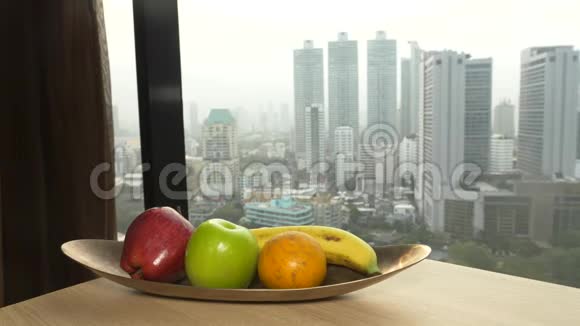 手把苹果从盘子里拿出来靠在窗户上看着摩天大楼4k慢动作视频的预览图