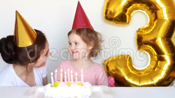 快乐的妈妈和孩子在聚会上吹灭生日蛋糕上的蜡烛她的女儿微笑着笑着拍手视频的预览图