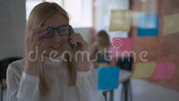 一个成功的女孩中弹严肃的商业女性在电话上交谈和在贴纸上做笔记的肖像视频的预览图