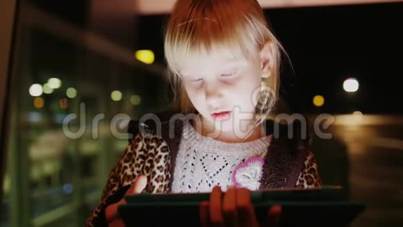 在等航班孩子在平板电脑上玩傍晚时分在机场视频的预览图