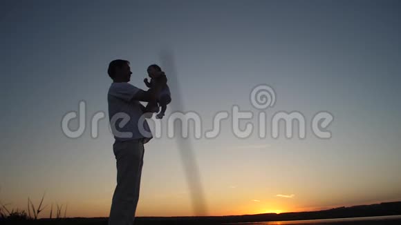 父亲在金色的夕阳下和婴儿玩耍视频的预览图