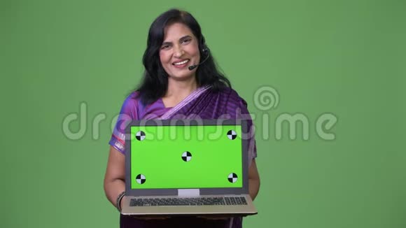 成熟快乐美丽的印度女人显示笔记本电脑的呼叫中心代表视频的预览图