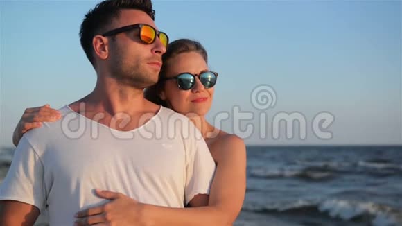 神奇的金发美女拥抱她的男朋友站在海滩附近的阳光明媚的夏日视频的预览图