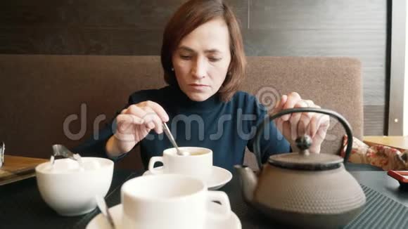 咖啡馆里的一个女孩在一杯茶里搅拌糖一个女人正在咖啡馆里喝绿茶视频的预览图