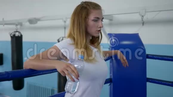 在拳击场上进行了艰苦的锻炼后口渴的女运动员从瓶子里喝水视频的预览图