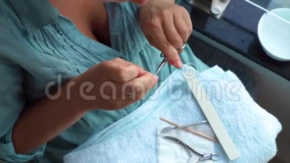 女性使用指甲剪刀剪角质层和归档指甲与指甲文件同时家庭修剪指甲快关门家庭视频的预览图