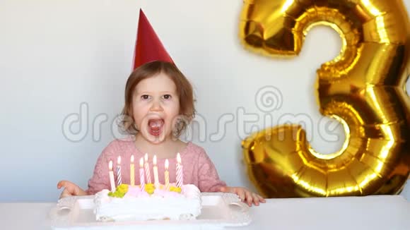 有趣的快乐孩子许愿在聚会上吹灭生日蛋糕上的蜡烛可爱的小女孩戴着粉红色的帽子微笑着视频的预览图