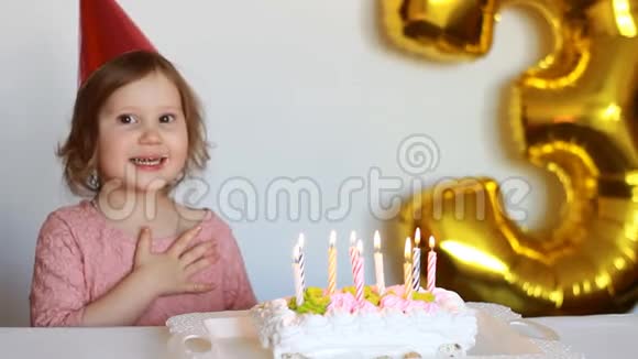 有趣的快乐孩子许愿在聚会上吹灭生日蛋糕上的蜡烛可爱的小女孩戴着粉红色的帽子微笑着视频的预览图