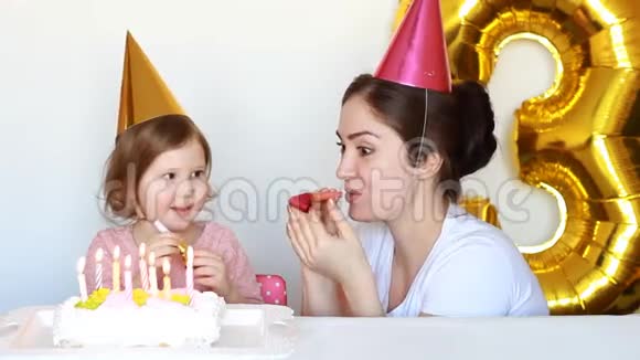 快乐的妈妈和孩子在聚会上吹灭生日蛋糕上的蜡烛她的女儿微笑着笑着拍手视频的预览图